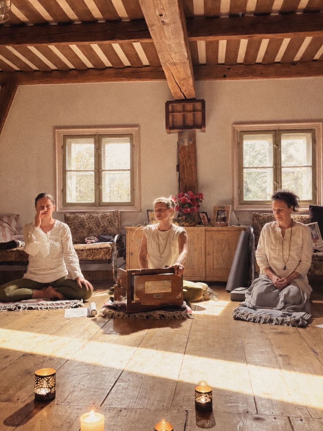 Účastnice Jivamukti Yoga Retreatu sedí se zpěvníkem u harmonia ve světnici se svícemi